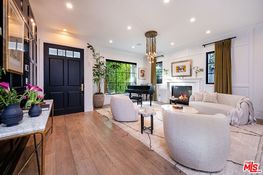The great room of 320 N Alta Vista, with a marble fireplace, oak floors, and tall steel-frame windows opening to the garden.